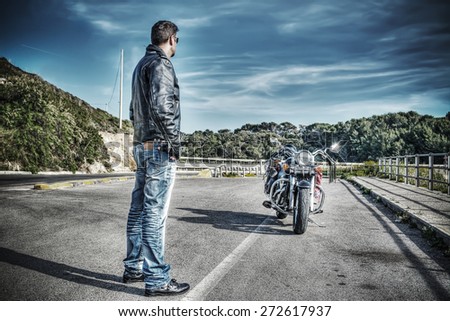 biker standing next to a classic motorcycle in hdr tone mapping effect