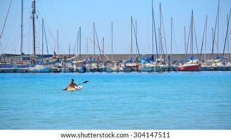 woman kayaking by Alghero harbor, Italy