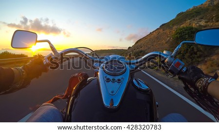 biker riding a classic motorcycle at sunset