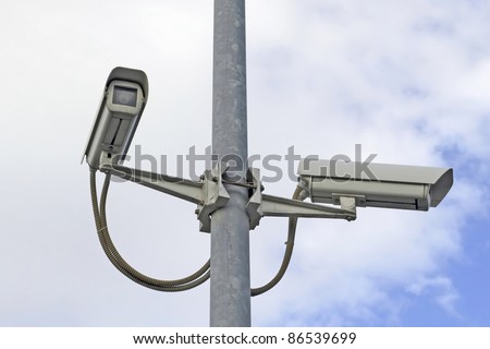 two security cameras on a street pole