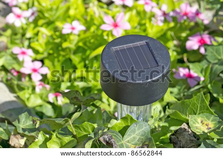 small solar garden light in a flower bed with stones