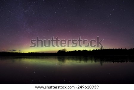 Colorful northern lights with reflections on water surface.