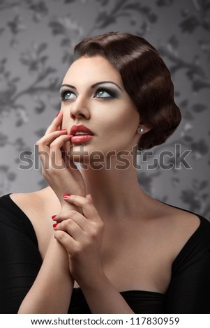 Classic retro style portrait of young beautiful brunette woman looking away touching lips