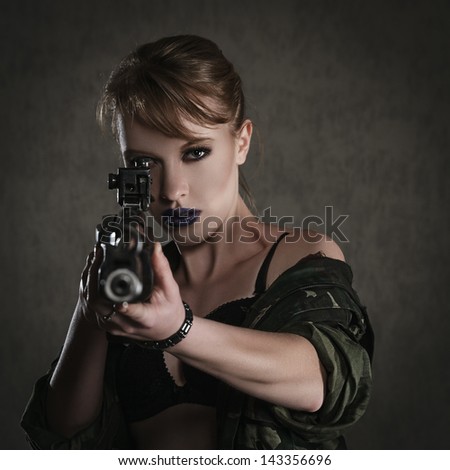 Beautiful young woman with a rifle against dark background