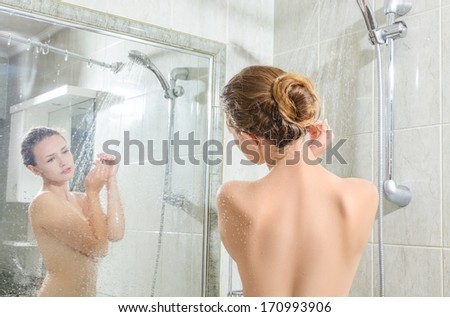 Young woman washing body in a shower. Rear view