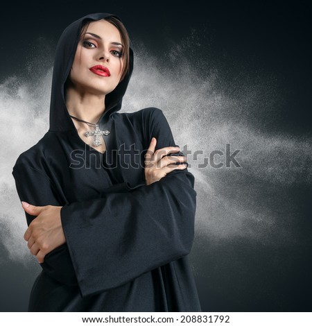 Young sad beautiful woman in black hood with cross