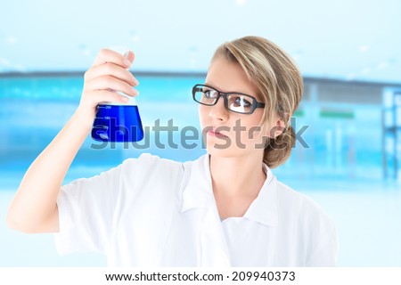 Scientist or student examining blue liquid in vial during scientific chemistry experiment