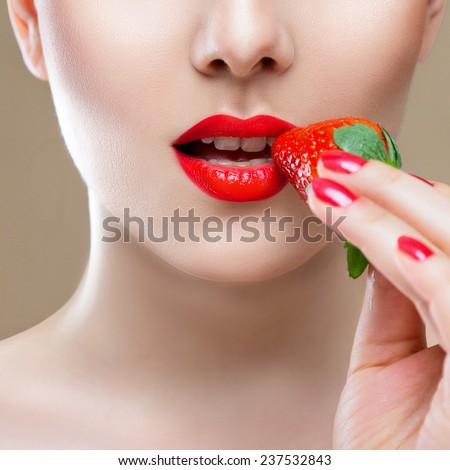 Young woman face lips close-up eating red ripe strawberry