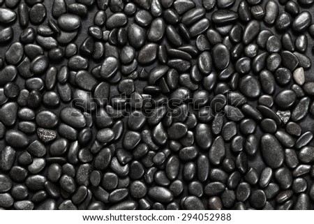 Abstract background of black pebble stones arranged on black surface