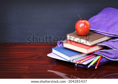 Books, apple, backpack and pencils on wood desk table and black board. back to school concept