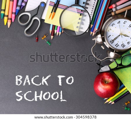 Books, apple, alarm clock and pencils on black board background with text Back to school concept