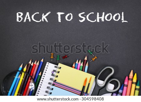 notebook, exercise book, scissors and pencils on black board background with text Back to school concept