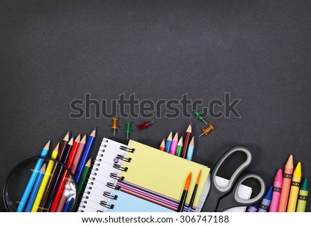 notebook, exercise book, scissors and pencils on black board background. Back to school concept