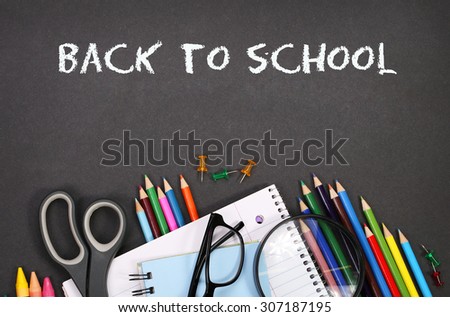 notebook, exercise book, scissors and pencils on black board background with text Back to school concept