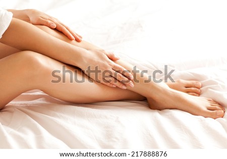 Close up of a perfect female legs. Woman applying moisturizer.
