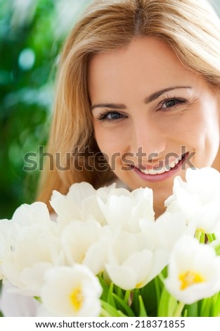 Close up of a beautiful young woman smelling white tulips