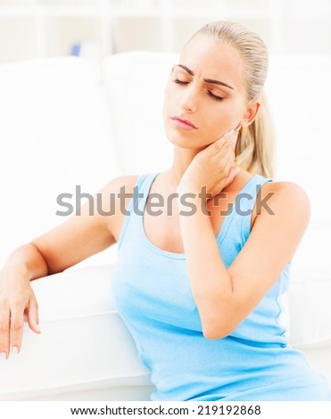 Beautiful young woman having neck pain and massaging her neck.