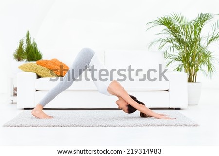 Woman practising yoga at home - Downward Facing Dog - Adho Mukha Svanasana