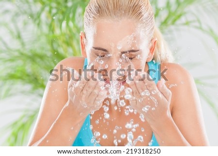 Happy young woman splashing water over her face.