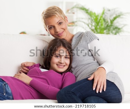 Mother an daughter sitting on the sofa in their living room.