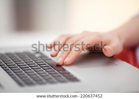 Close up of a female hand touching touch pad of a laptop.