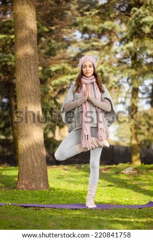 Young woman practising yoga in the park - tree pose.