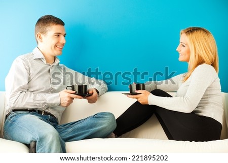 Young man and woman drinking coffee or tea in the living room.