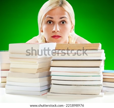 Close up of two piles of books against green background. Scared student in the background.