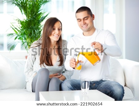 Young man and woman drinking freshly squeezed juice in the living room.