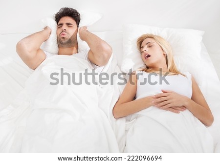 Man is trying to fall a sleep while woman is snoring.