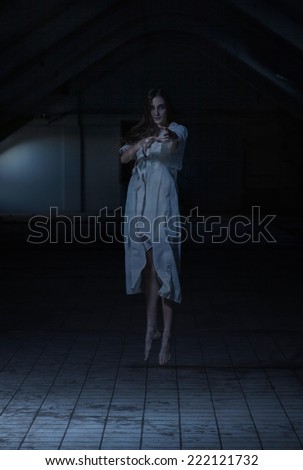 Scary ghost of a woman levitating in an empty dark room.