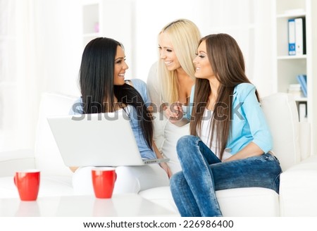 Three friends looking at computer tablet and laughing.
