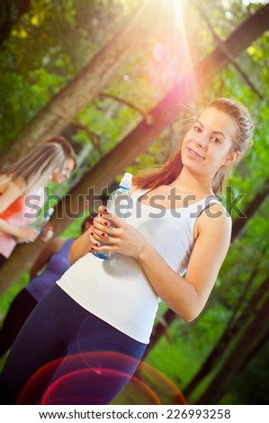 NO FLARE ADDED. This photo was not post processed. Young beautiful fit woman standing in nature. Other women in background.