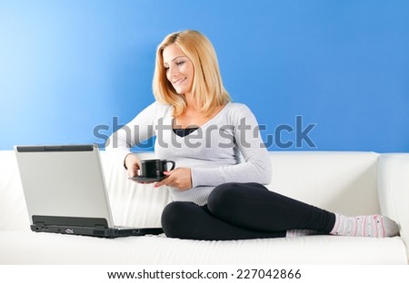 Young beautiful woman sitting on the sofa and working on laptop.