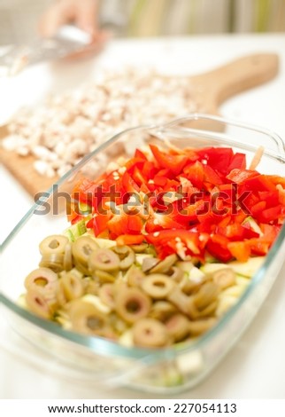 Chopped vegetables prepared for cooking. Focus on chopped olives and peppers.