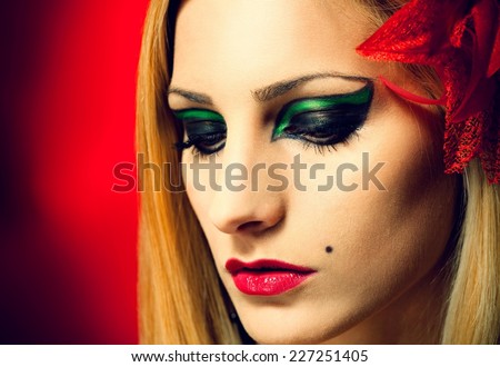 Stylish woman with a red flower in her hair posing - backlit by red light.