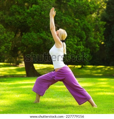 Young woman practising yoga in the park - warrior I.