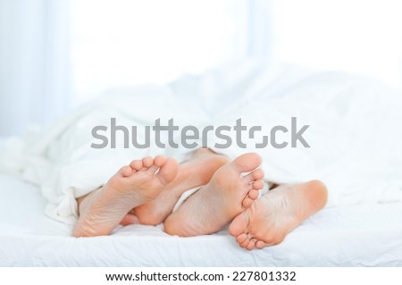 Couple\'s feet poke out at the bottom of a bed.