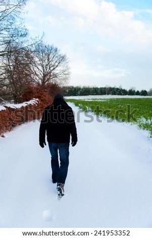 Man walking in the snow at the countryside.