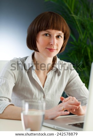 Middle aged woman in the office working on a laptop.