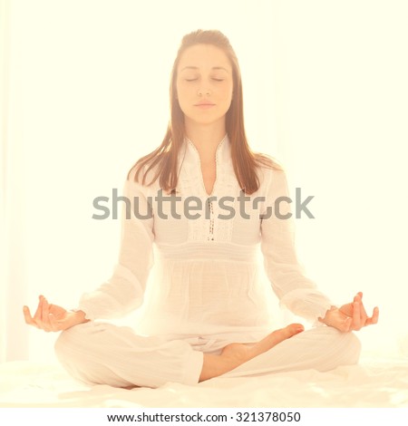 Young girl meditating in half lotus - light background, copy space.