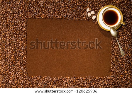 Frame made of roasted coffee with grounded inside and beans outside, small cup of coffee standing in the corner