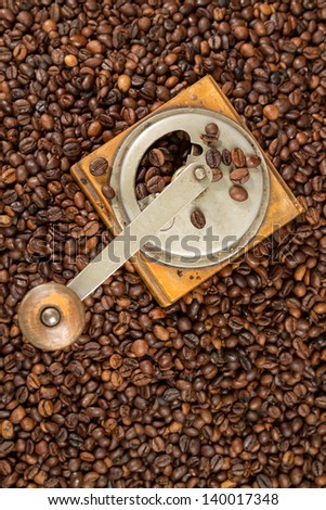 Old coffee mill covered with coffe beans
