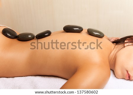 Stone therapy. Woman getting a hot stone massage in spa salon