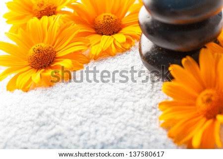 Spa stones on white towel with orange golden-daisy flower