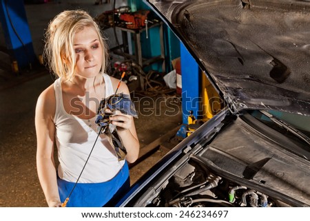 Girl checks the oil level in their own broken car