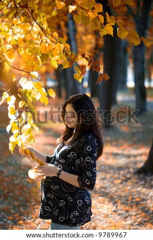 Pregnant woman hold tree branch in autumn park