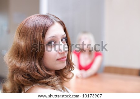 Girls discuss your secret in office. One girl half turn and looking at camera