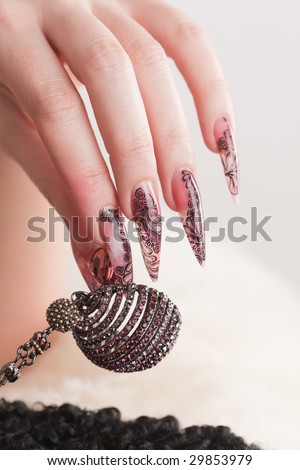 Human hand with long fingernail and beautiful manicure hold beads over gray