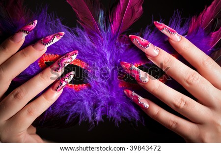 Human fingers with long fingernail and beautiful manicure holding venetian mask